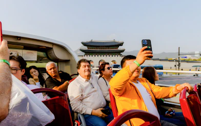 Open-top bus tourists near Gwanghwamun Gate, Seoul, on Yellow Balloon City Bus tour.