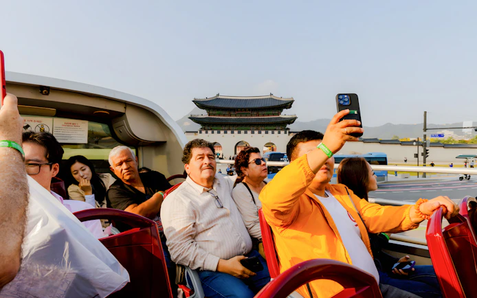 Open-top bus tourists near Gwanghwamun Gate, Seoul, on Yellow Balloon City Bus tour.