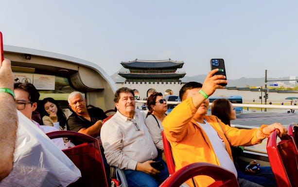 Open-top bus tourists near Gwanghwamun Gate, Seoul, on Yellow Balloon City Bus tour.