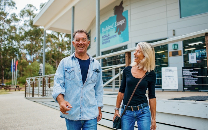 Visitors smiling outside Koala Conservation Reserve entrance, Phillip Island Nature Parks.
