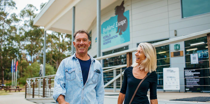 Visitors smiling outside Koala Conservation Reserve entrance, Phillip Island Nature Parks.