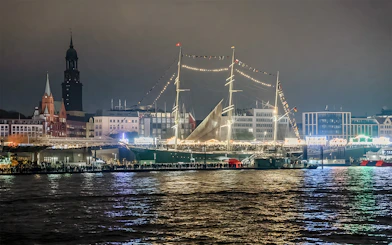 Grand Harbor illuminated at night with a tall ship and city skyline during evening lights cruise.