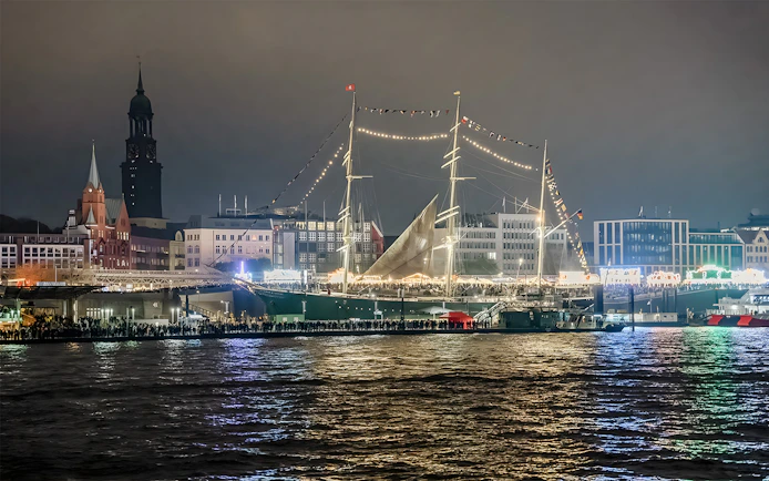 Grand Harbor illuminated at night with a tall ship and city skyline during evening lights cruise.