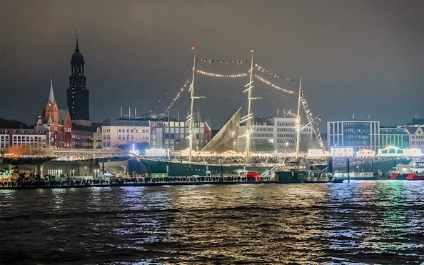 Grand Harbor illuminated at night with a tall ship and city skyline during evening lights cruise.