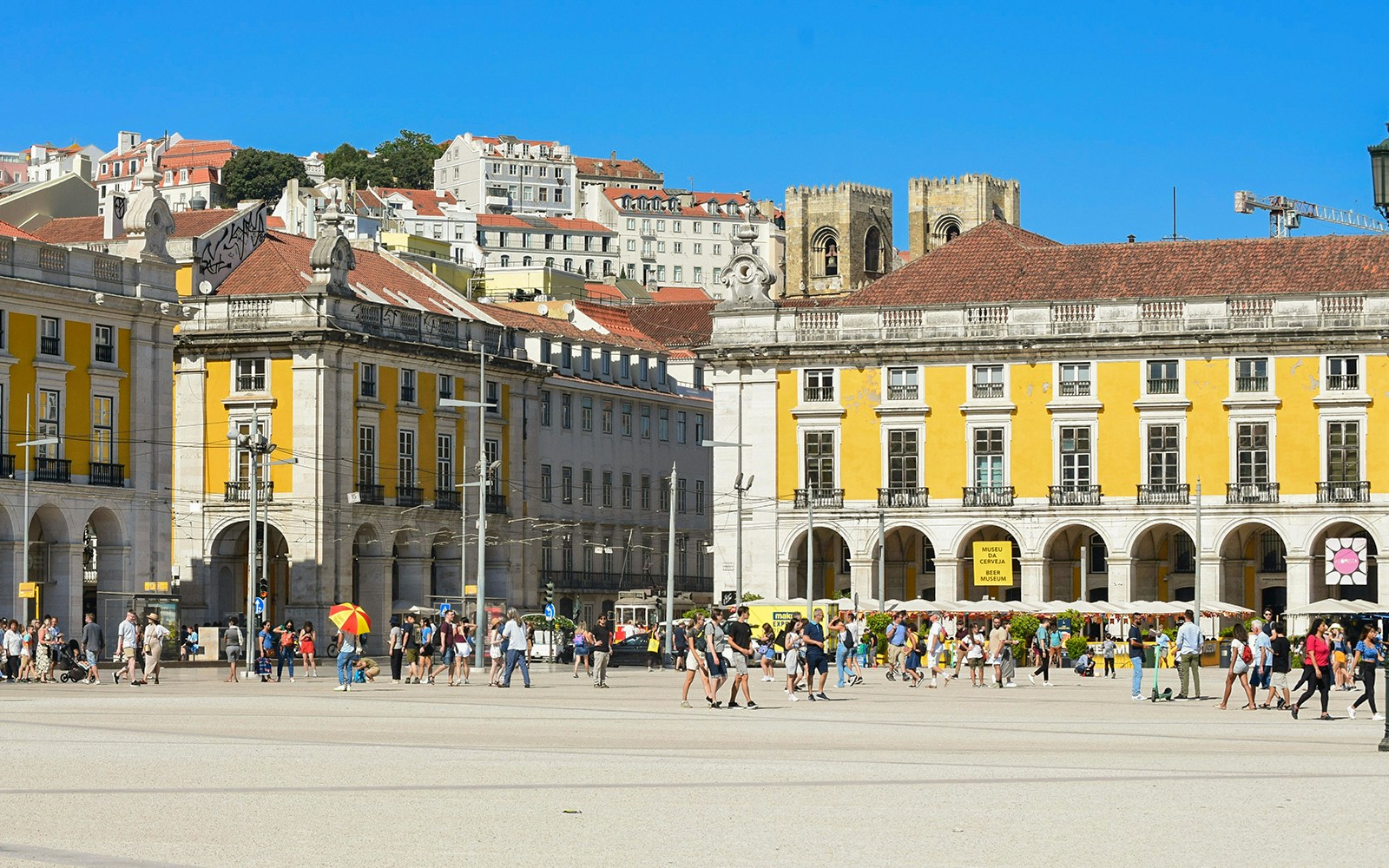 Crowd at Praça do Comércio in Lisbon with historic yellow buildings in the background.