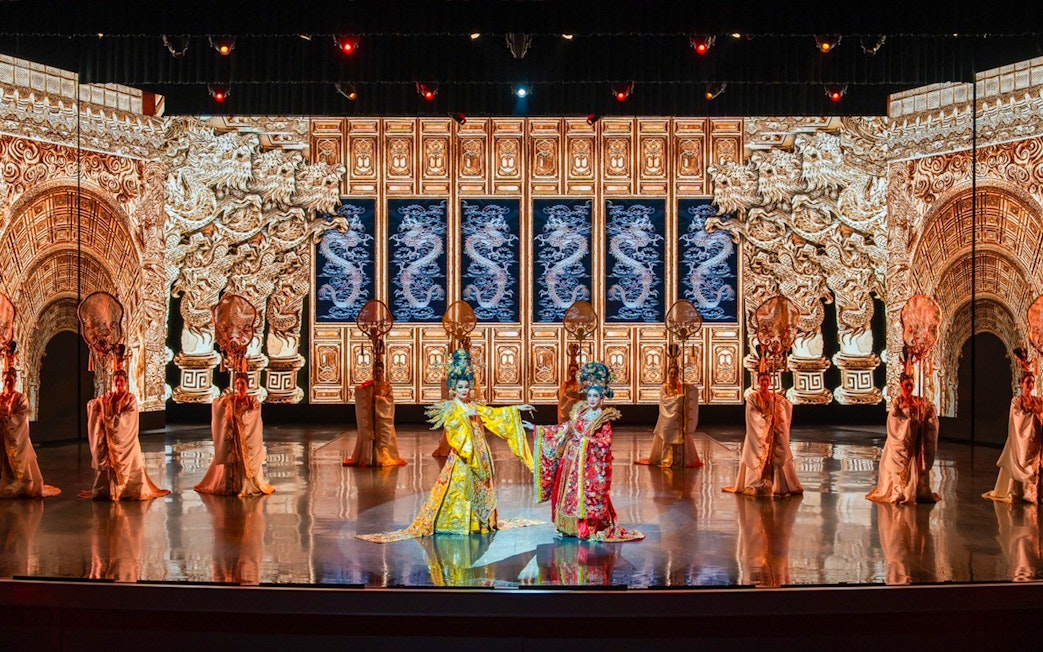 Traditional Chinese performance with ornate costumes and dragon backdrop at The Colosseum.