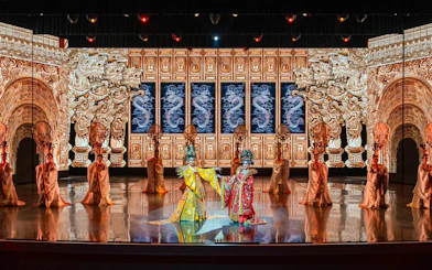 Traditional Chinese performance with ornate costumes and dragon backdrop at The Colosseum.