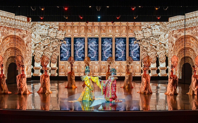 Traditional Chinese performance with ornate costumes and dragon backdrop at The Colosseum.
