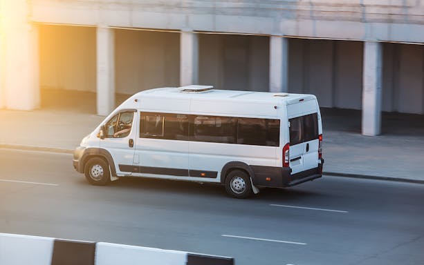Private airport transfer van in Bangkok on a city road.