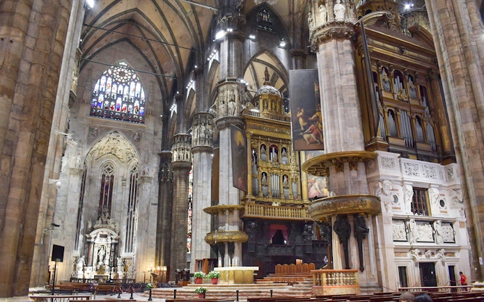Interior view of Duomo Milan Cathedral featuring ornate columns and stained glass windows.