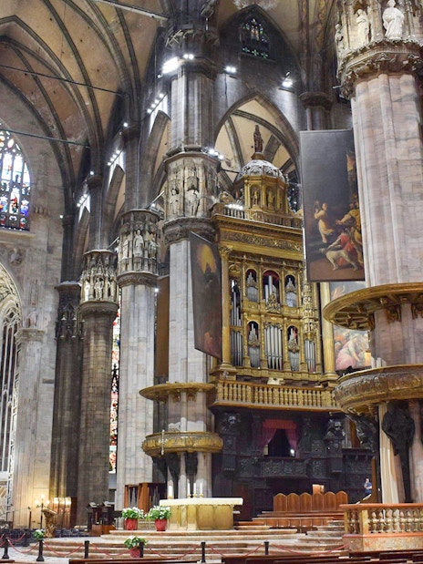 Interior view of Duomo Milan Cathedral featuring ornate columns and stained glass windows.