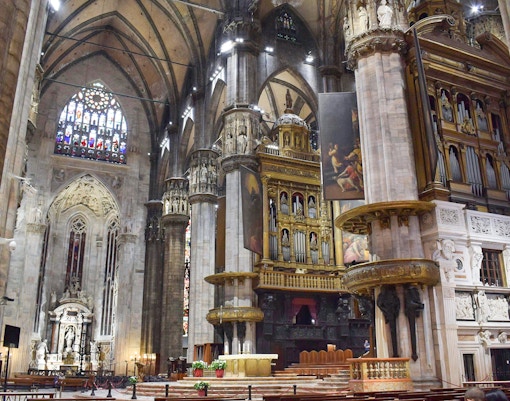 Interior view of Duomo Milan Cathedral featuring ornate columns and stained glass windows.