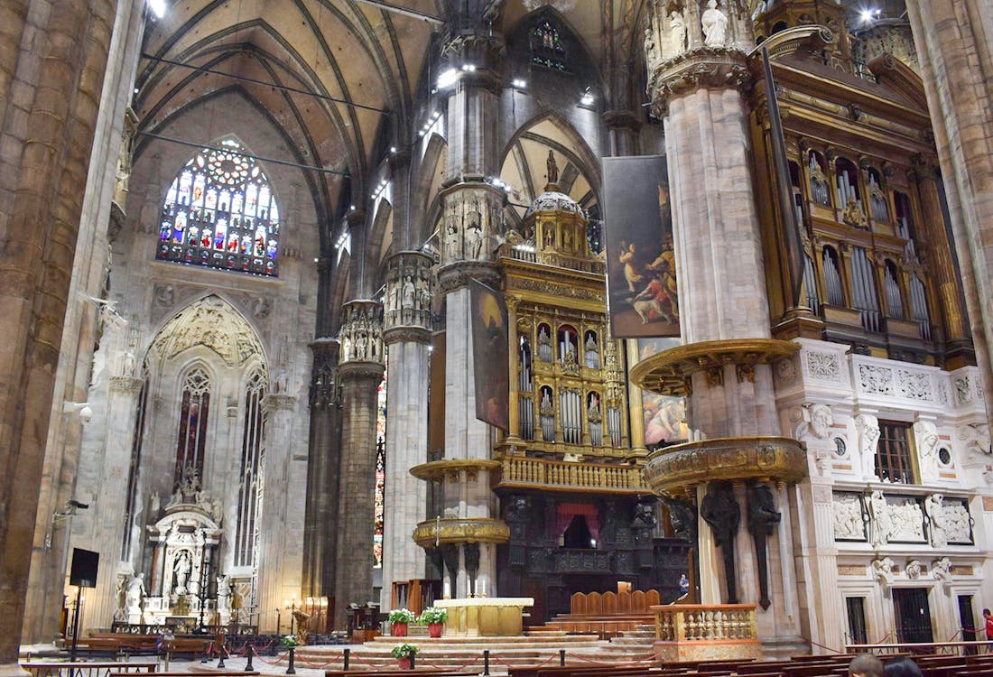 Interior view of Duomo Milan Cathedral featuring ornate columns and stained glass windows.