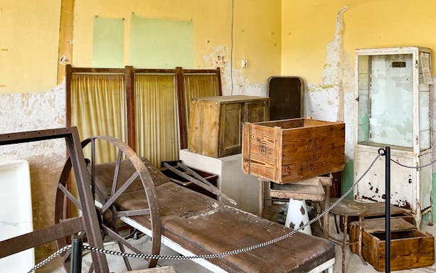 Interior of Auschwitz sub-camp with wooden crates and old medical equipment.