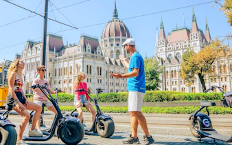 E-scooter tour group in front of the Hungarian Parliament Building, Budapest.