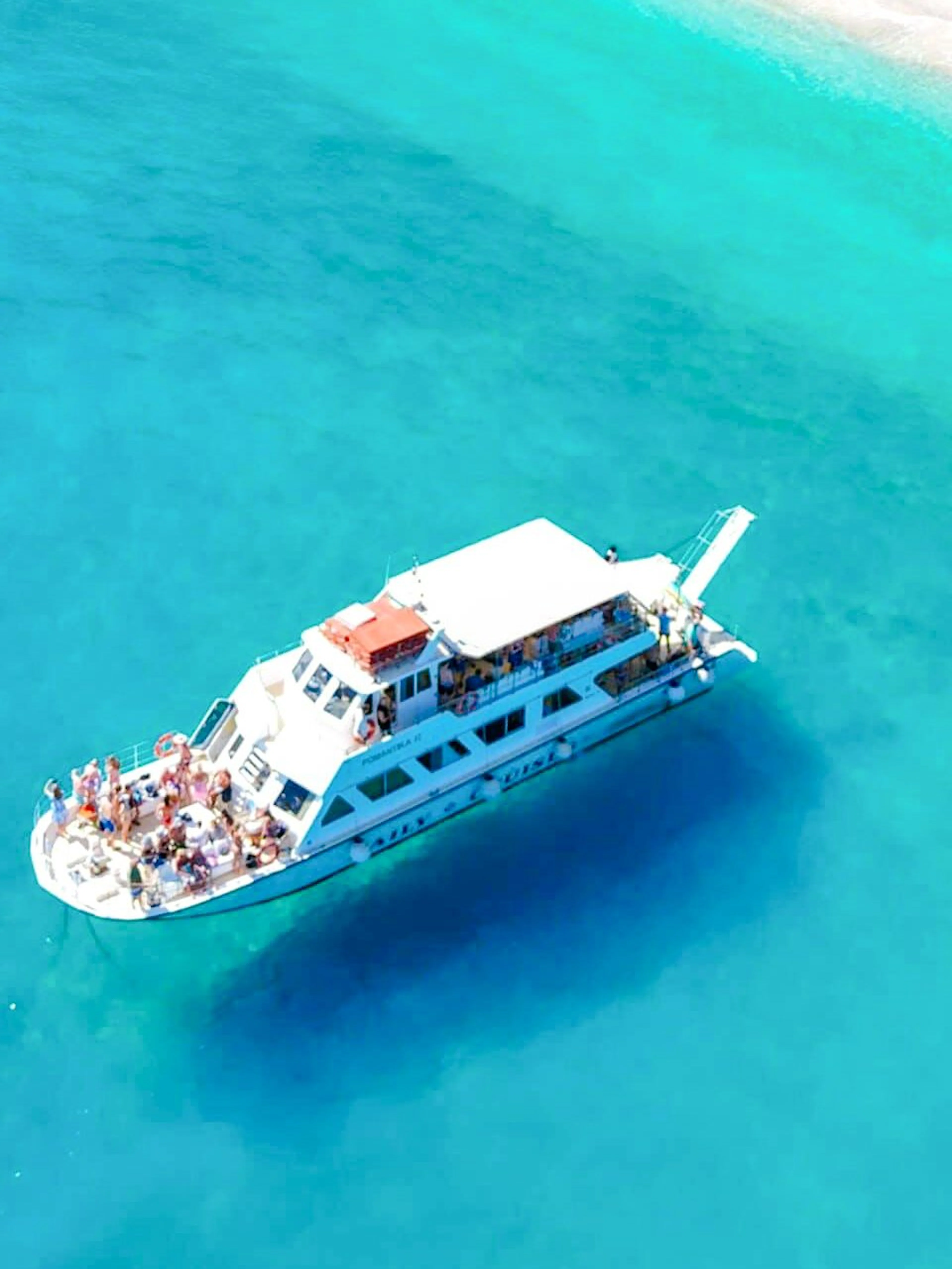 Aerial view of a cruise ship near Ithaca's turquoise coastline.