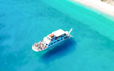 Aerial view of a cruise ship near Ithaca's turquoise coastline.