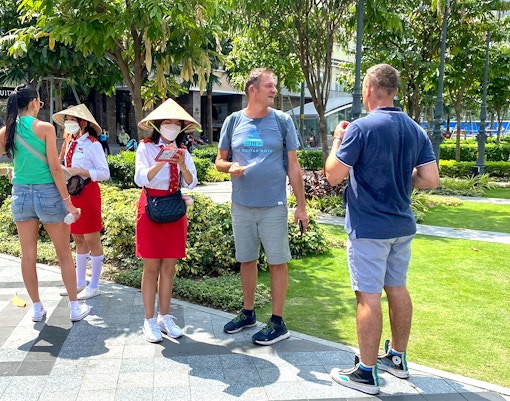 Tourists receiving brochures from guides in traditional hats, Saigon Hop-on Hop-Off Sightseeing Tours.