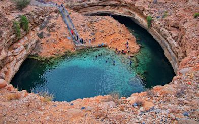 Visitors swimming in the turquoise waters of Bimmah Sinkhole, Oman.