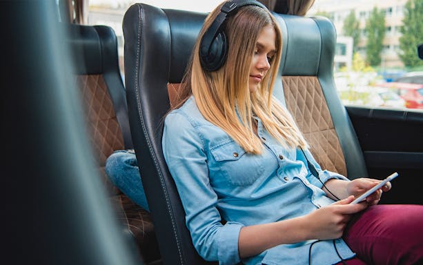 Passenger relaxing with headphones on a National Express bus.
