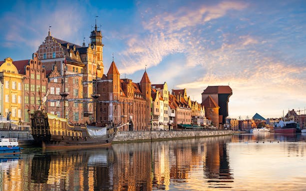 Gdansk waterfront with historic buildings and a ship at sunset, Poland.