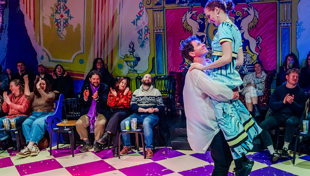 Couple dancing in front of an audience at a vibrant theater performance of Plied and Prejudice.