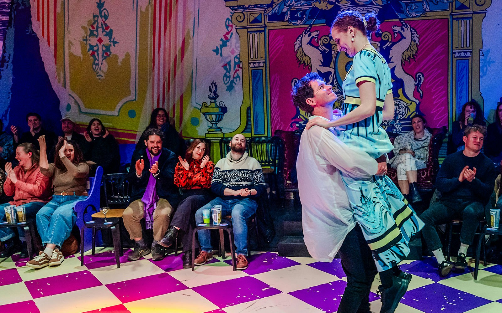 Couple dancing in front of an audience at a vibrant theater performance of Plied and Prejudice.