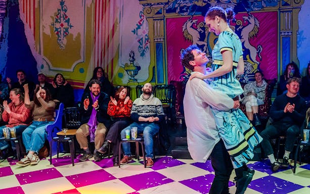 Couple dancing in front of an audience at a vibrant theater performance of Plied and Prejudice.