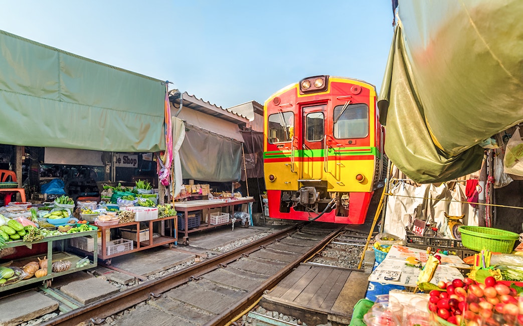Train passing through Umbrella Fresh Market on the railroad track, Mae Klong Train Station, Bangkok.