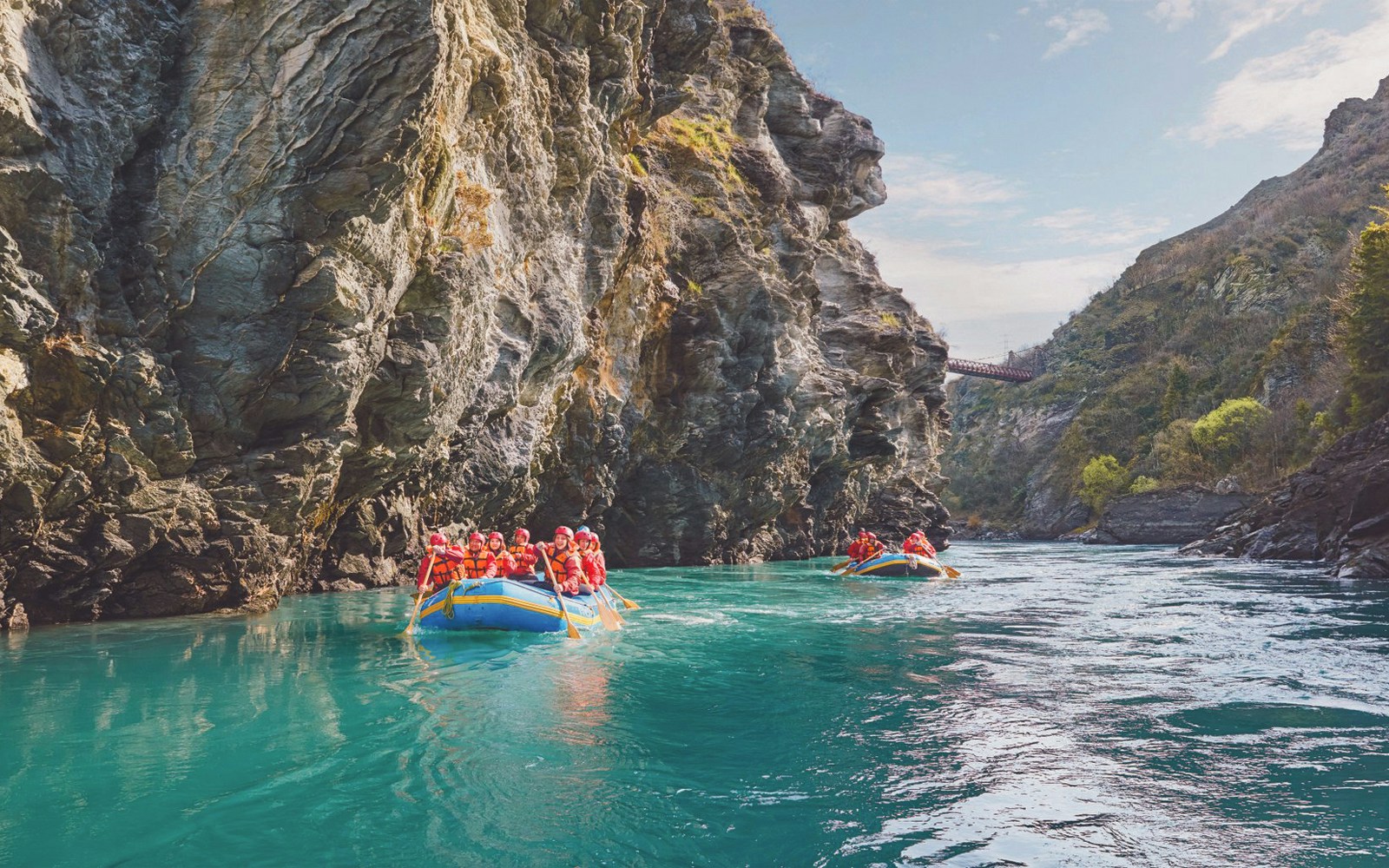 Tourists rafting on Kawarau River between rocky cliffs in New Zealand.