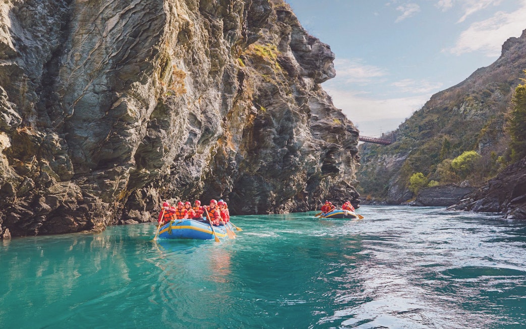 Tourists rafting on Kawarau River between rocky cliffs in New Zealand.
