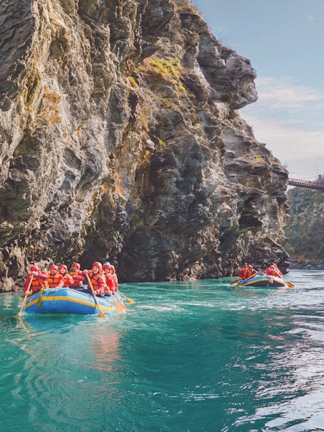 Tourists rafting on Kawarau River between rocky cliffs in New Zealand.
