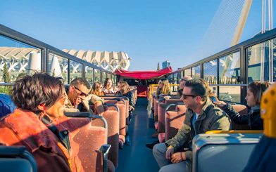 Valencia hop-on hop-off bus with tourists enjoying city views.