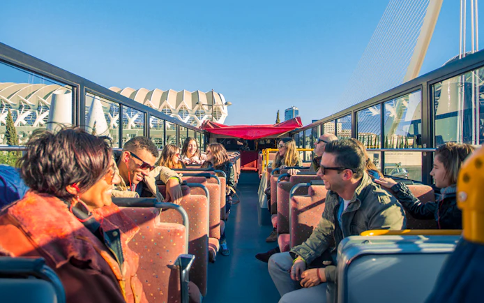 Valencia hop-on hop-off bus with tourists enjoying city views.