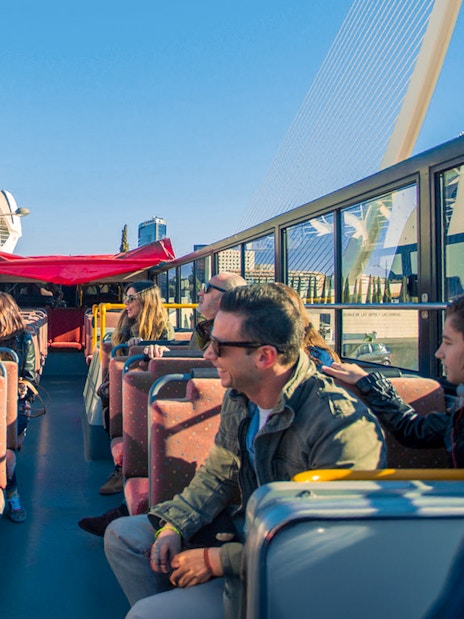 Valencia hop-on hop-off bus with tourists enjoying city views.