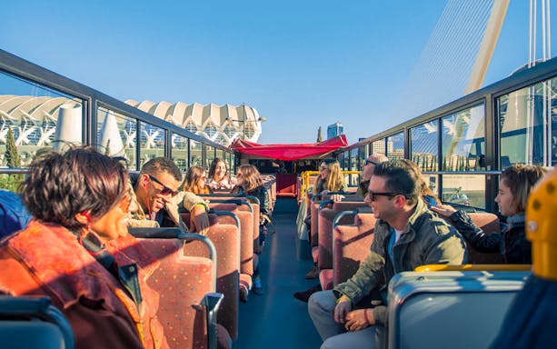 Valencia hop-on hop-off bus with tourists enjoying city views.
