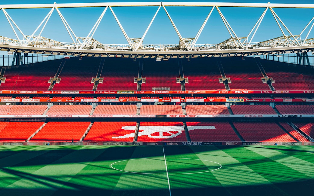 Arsenal FC Emirates Stadium interior with empty red seats and field.