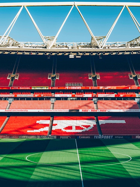 Arsenal FC Emirates Stadium interior with empty red seats and field.