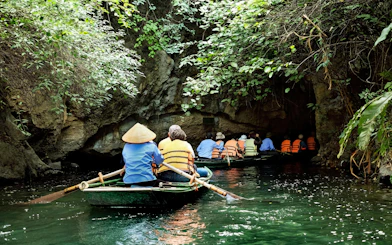 Tourists in small boat entering cave on Trang An River, Ninh Binh, Vietnam.