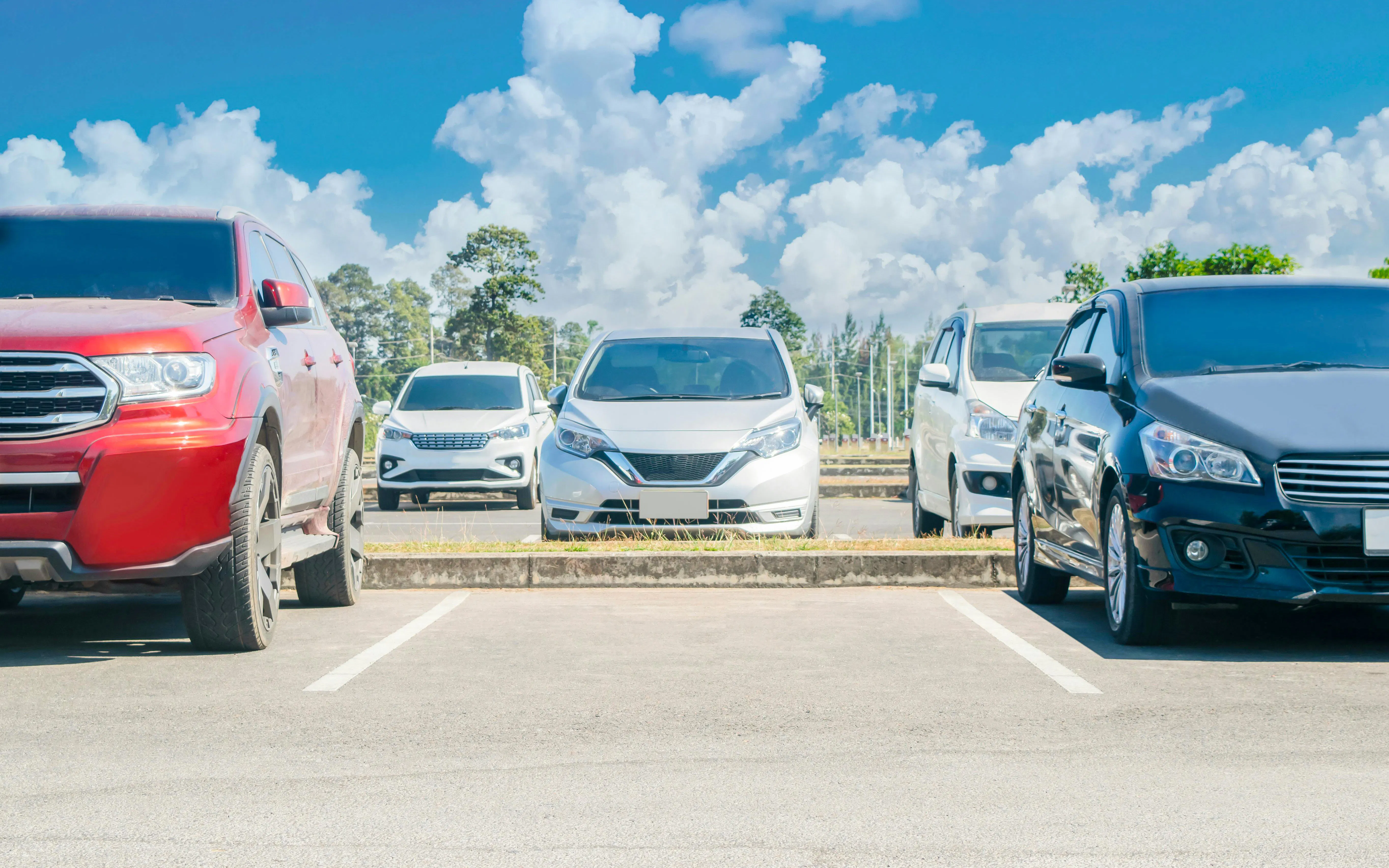 Cars parked in a lot under a clear blue sky.