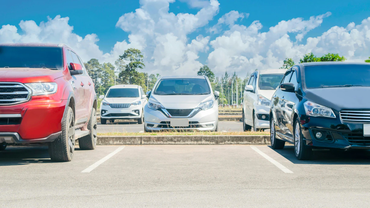Cars parked in a lot under a clear blue sky.