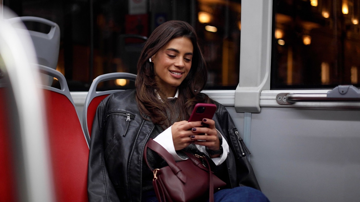 Young woman using smartphone on a city bus at night.
