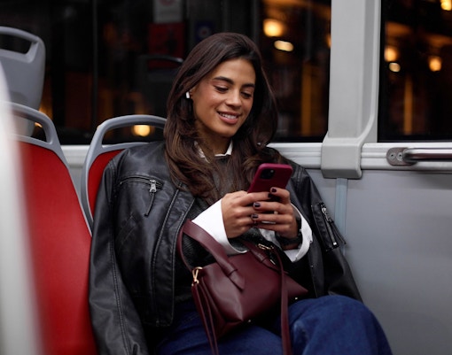 Young woman using smartphone on a city bus at night.