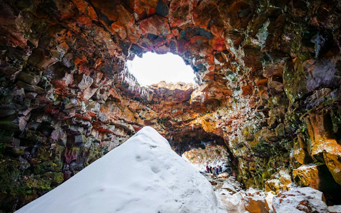 Inside Raufarhólshellir Lava Tunnel with snow and rock formations, Iceland.