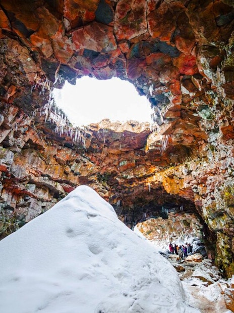 Inside Raufarhólshellir Lava Tunnel with snow and rock formations, Iceland.