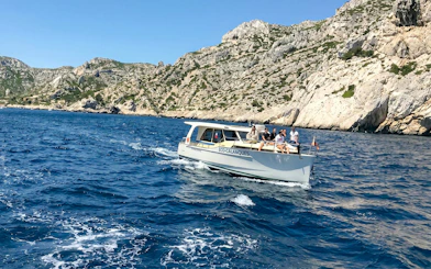 Excursion boat with tourists cruising in Calanques de Cassis, France.