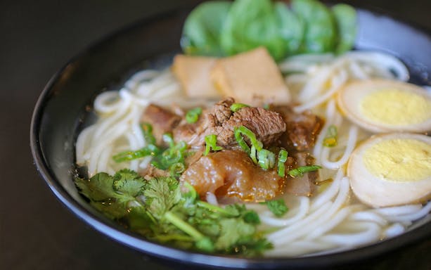 Ramen bowl with sliced egg, beef, and green onions on Tokyo Ultimate Ramen Tasting Tour.