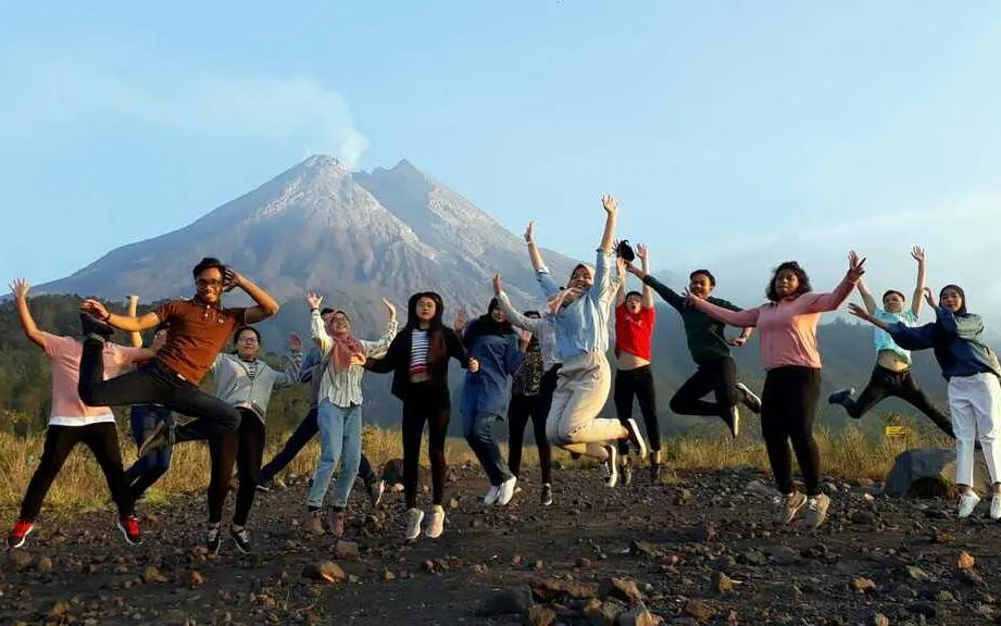 Group jumping with Mount Merapi in the background during Jeep Merapi Lava Tour at sunrise.