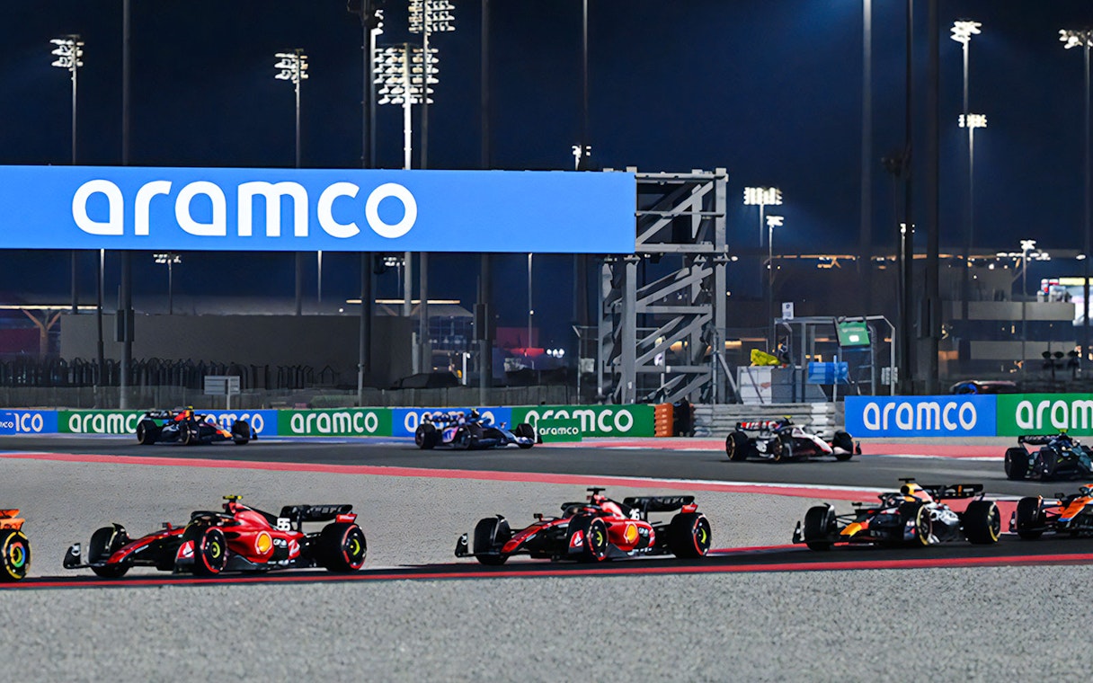 Formula 1 cars racing at night on the Qatar circuit.