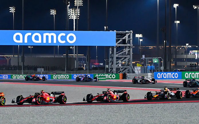 Formula 1 cars racing at night on the Qatar circuit.